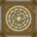 Symmetrical upward view of Qasr Al Watan's ornate dome in Abu Dhabi, with intricate geometric patterns, golden tones, and turquoise accents.